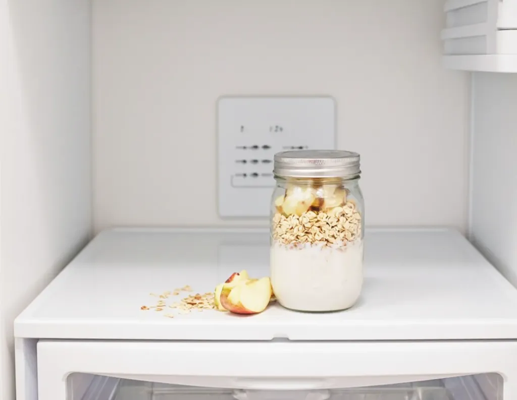Overnight oats jar being placed inside a refrigerator